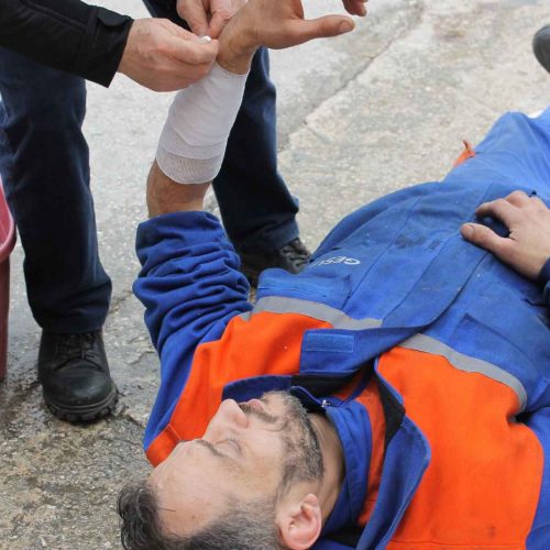 First responder bandaging an injured worker's wrist outdoors, demonstrating how first aid training saves lives