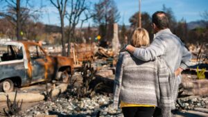First aid for natural disasters - person standing near disaster scene with fire damage