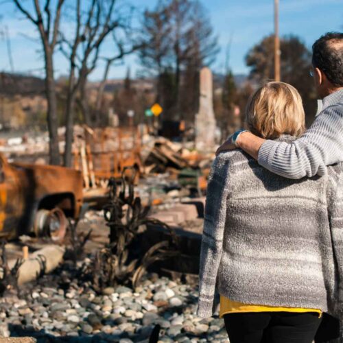 First aid for natural disasters - person standing near disaster scene with fire damage