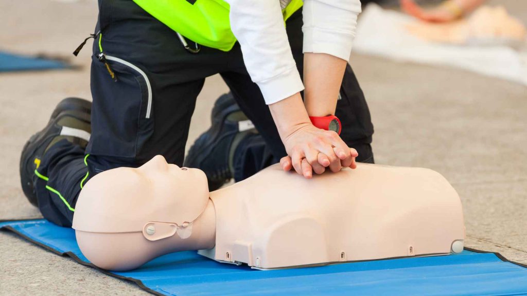close up of a person performing CPR on a manikin
