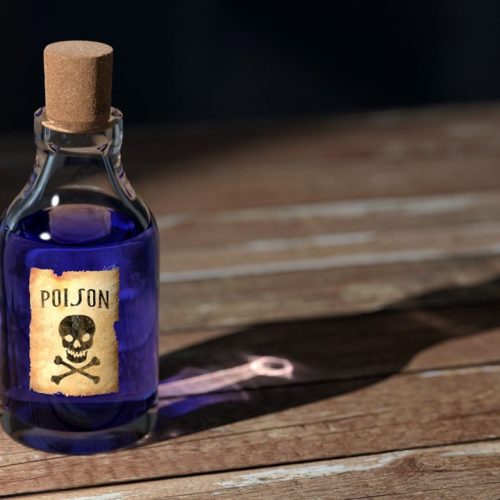 A small glass bottle with a cork stopper, filled with blue liquid. It has a label with a skull and crossbones and the word "POISON." The bottle casts a shadow on a wooden surface.