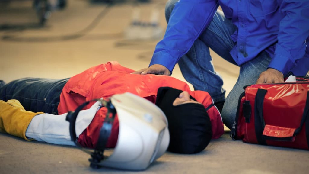 a first aider helping a person in a workplace environment