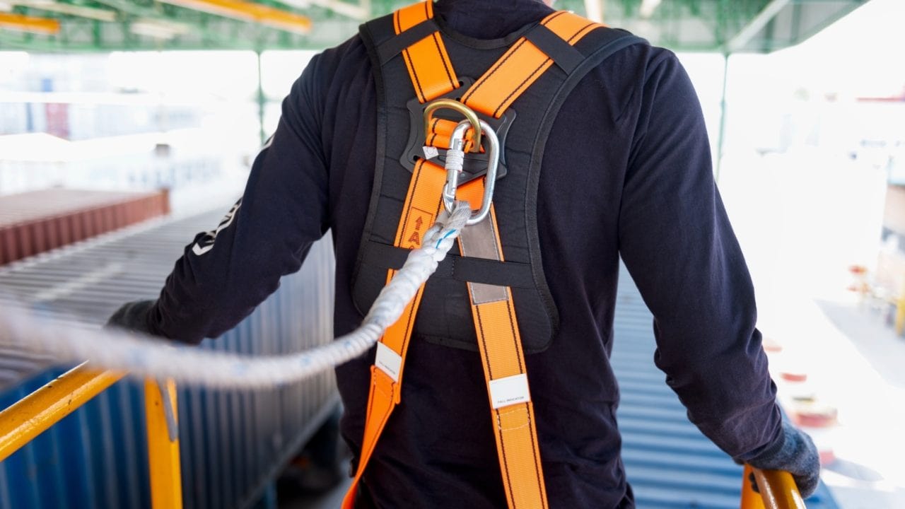 Close-up of a safety harness and carabiner clipped to a lifeline on a rooftop