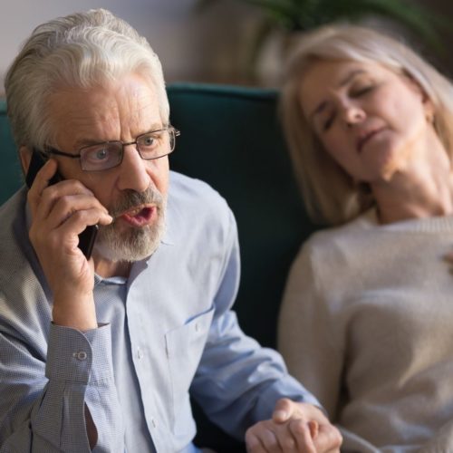 A man urgently calling 911 as his wife experiences chest pain, possibly indicating a heart attack
