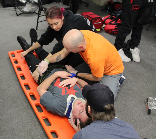 Students stabilizing a patient on a backboard during First Responder training in North York