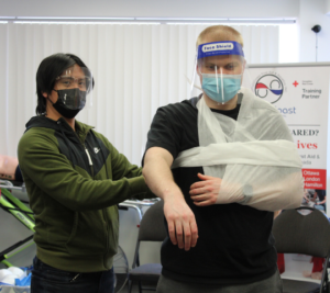 Applying an arm sling with a triangular bandage from a workplace first aid kit