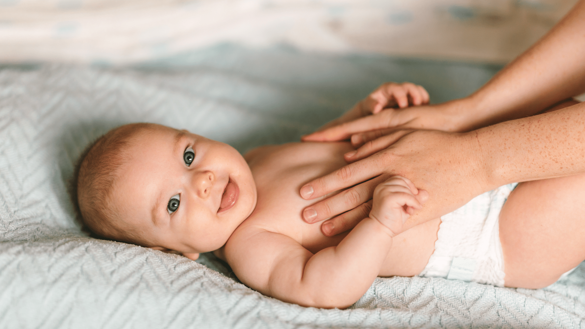 Smiling baby on bed.