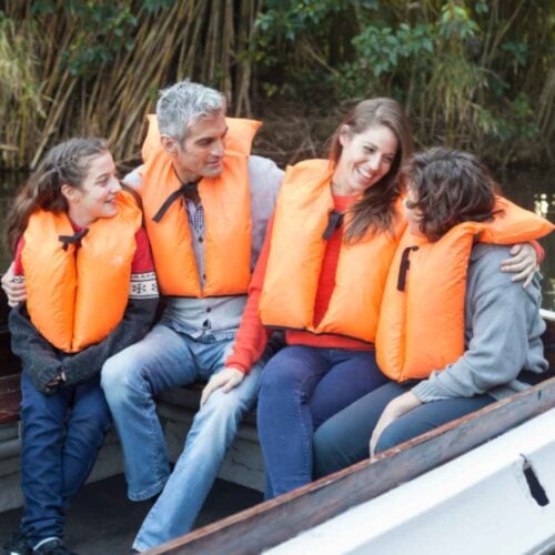 A family wearing PFDs enjoying boating in a lake.