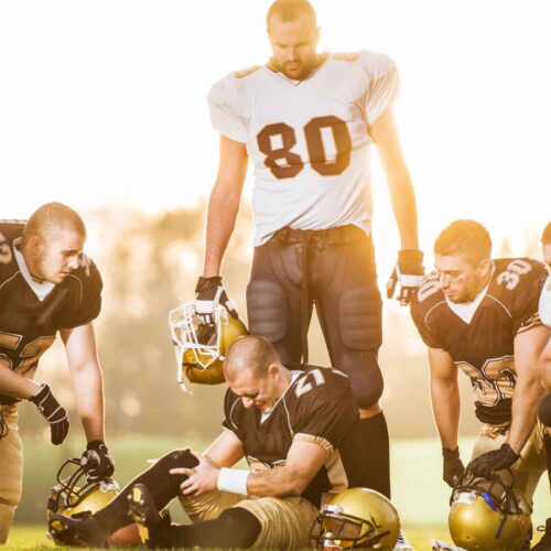 A group of soccer players in the field with one of them injured with sprain in the leg.