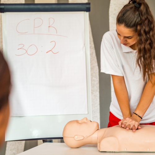 A lady performing CPR training on a mannequin