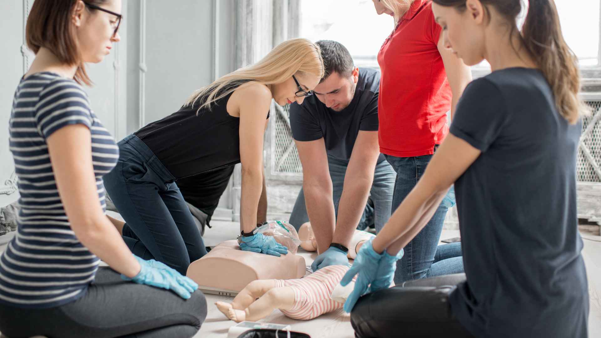 A team of professionals practicing CPR on manikins during a private group session