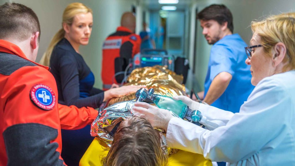 man being rushed through a hospital with a hospital blanket on due to hypothermia