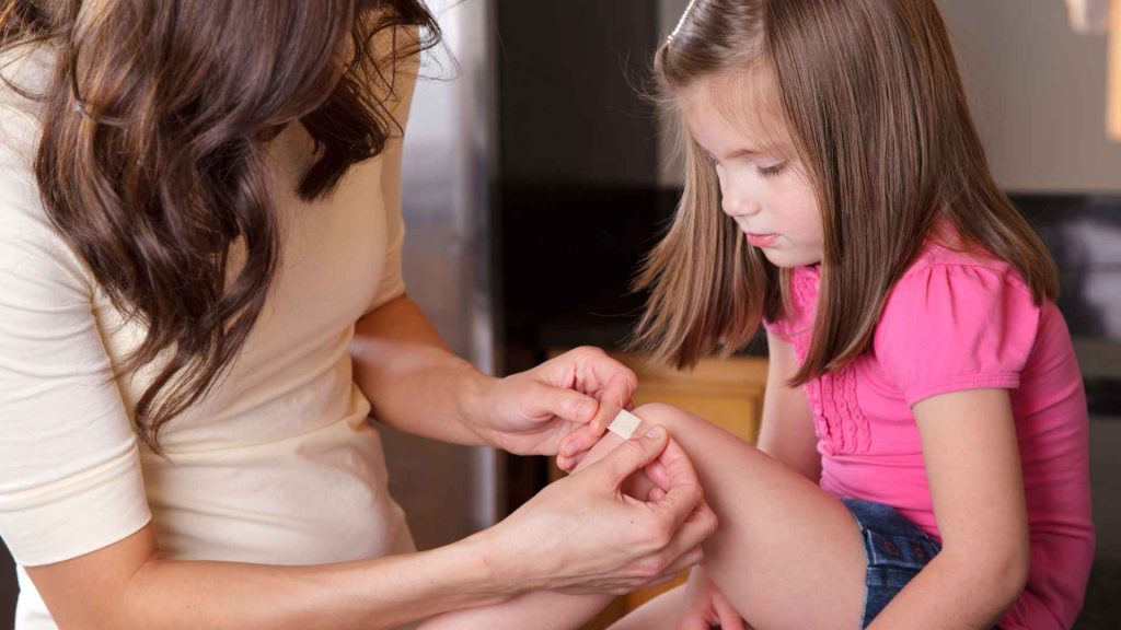 mother putting band aid on her daughter's knee