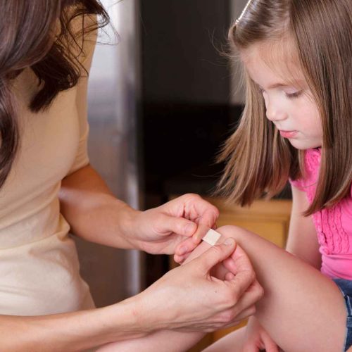 mother putting band aid on her daughter's knee