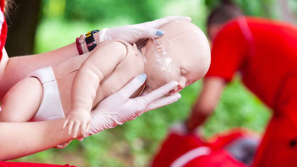 person performing back blows on an infant manikin