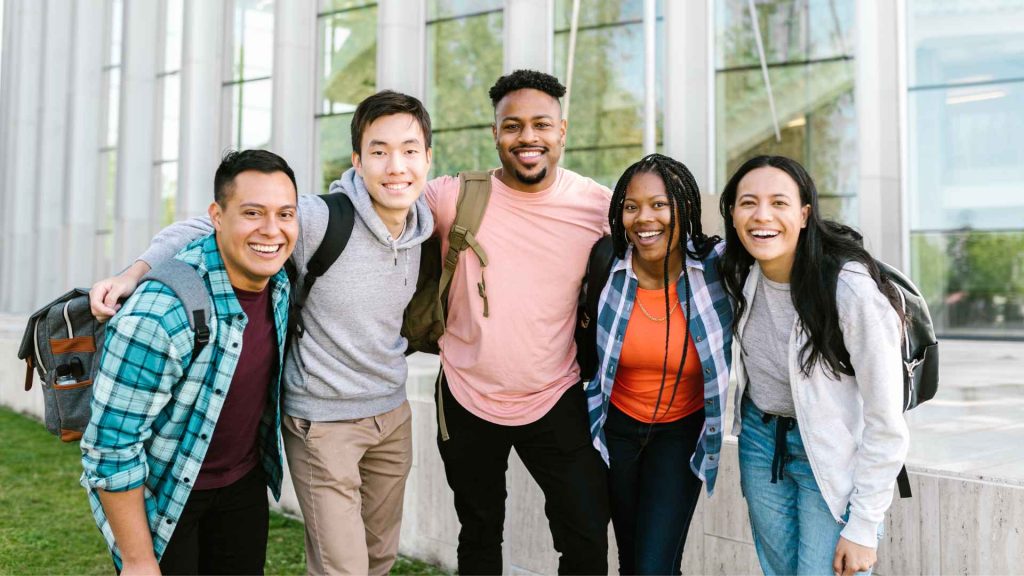 a diverse group of young adults posing for a picture together outside on a school campus