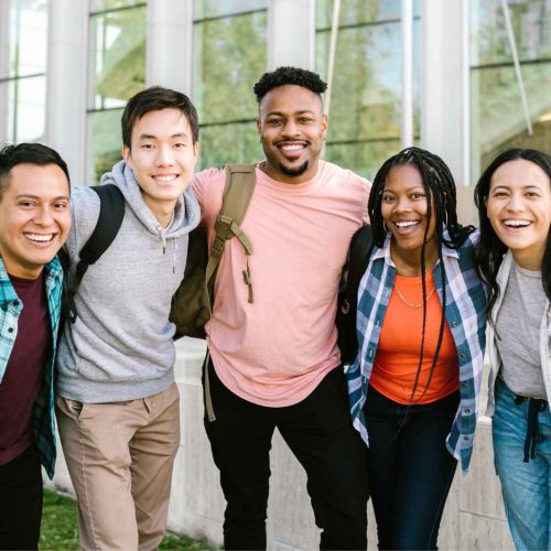 a diverse group of young adults posing for a picture together outside on a school campus