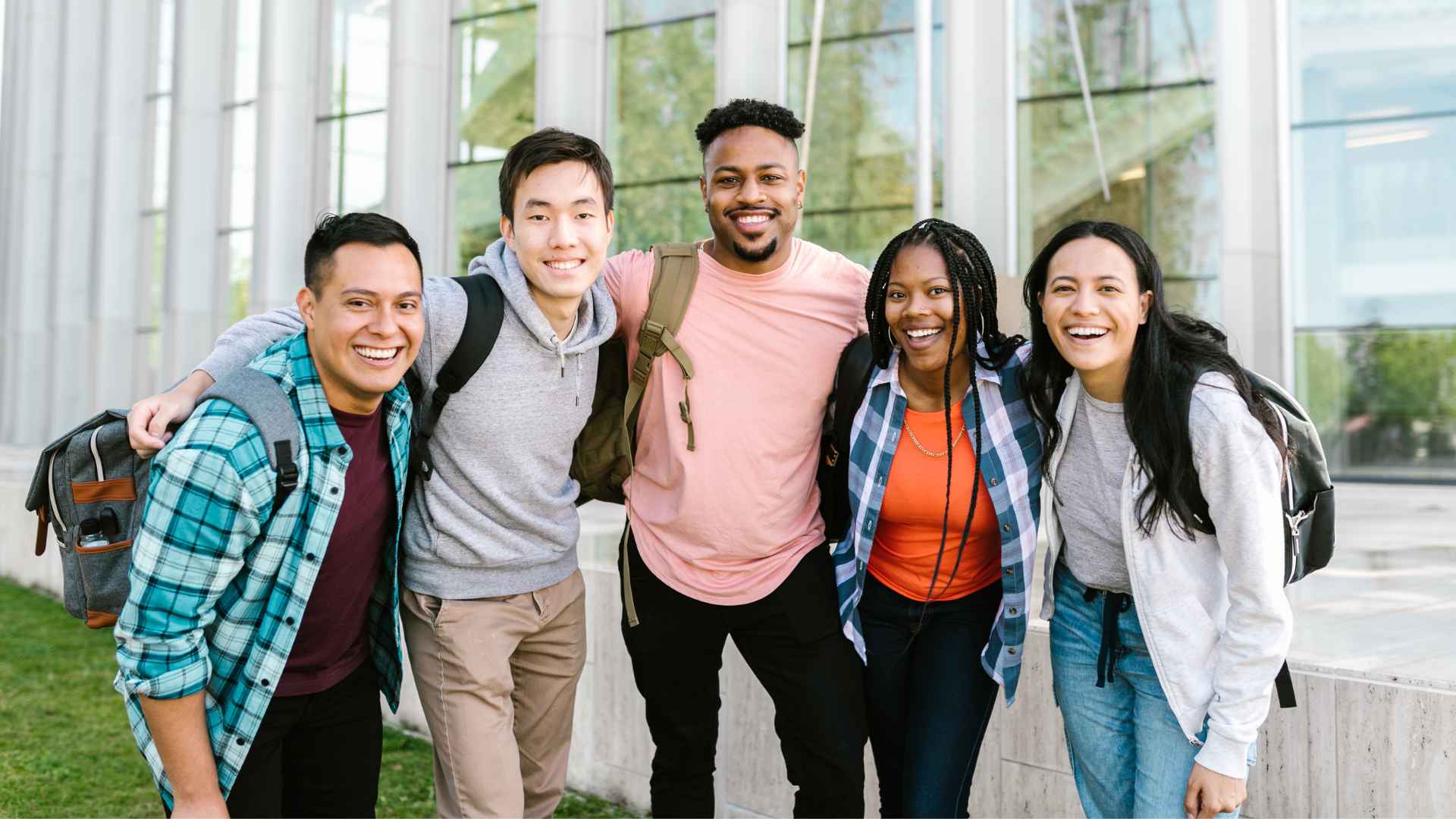 a diverse group of young adults posing for a picture together outside on a school campus