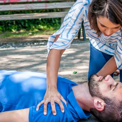 Woman performing CPR on a person outdoors, demonstrating Good Samaritan bystander first aid response in California