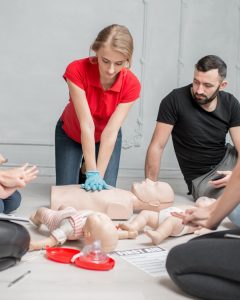 Woman in a red shirt practicing first aid skills during a first aid and CPR certification in Red Deer, Alberta with Coast2Coast