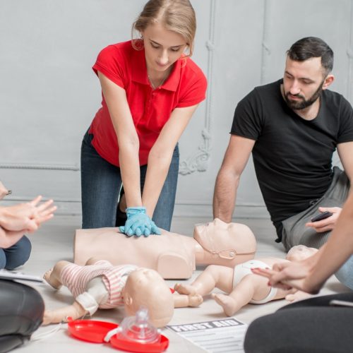 Woman in a red shirt practicing first aid skills during a first aid and CPR certification in Red Deer, Alberta with Coast2Coast