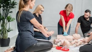 Group of adults practicing CPR on adult and infant manikins with a CPR face mask during a Red Deer first aid and CPR certification with Coast2Coast