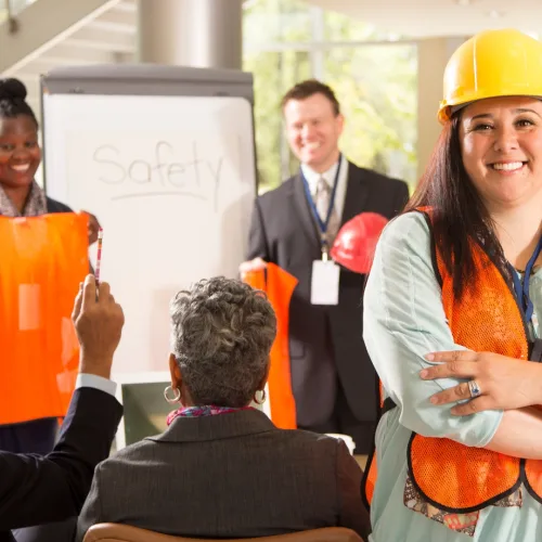 Workers in orange safety vests and hard hats attending a JHSC certification training session in a workplace safety classroom in Canada