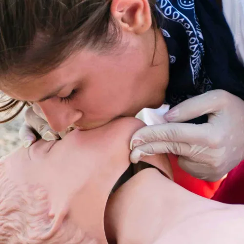 Lifeguard performing rescue breathing CPR on a casualty outdoors, highlighting why first aid and CPR training is essential for lifeguards