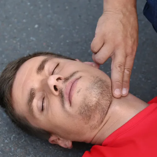 First aider performing head-tilt chin-lift airway management and pulse check on unconscious person during Coast2Coast first aid training