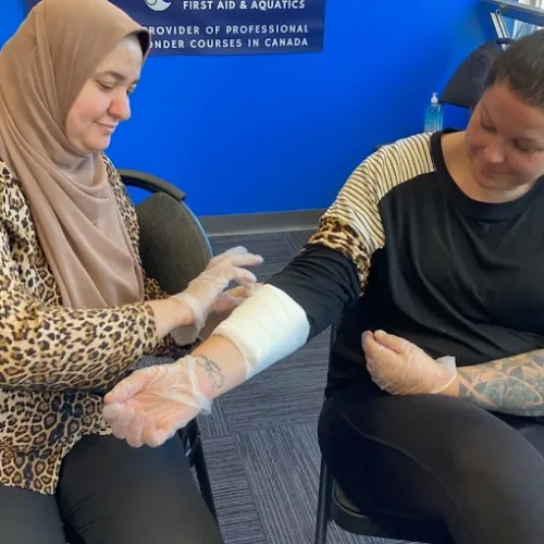 Two women practicing bandaging techniques during a First Aid and CPR training in Calgary by Coast2Coast First Aid